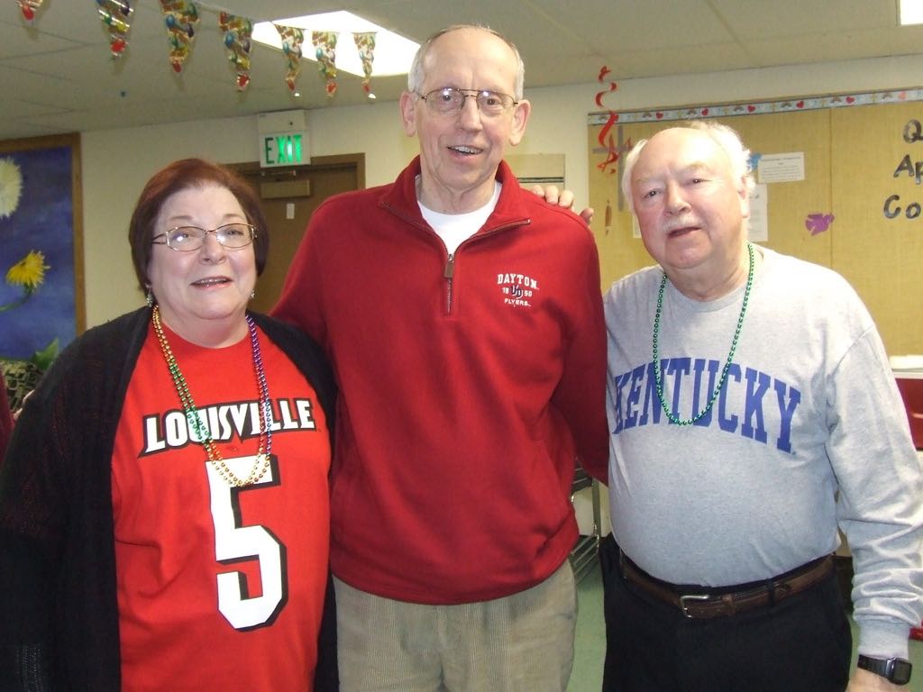 Bill & Mary Lou with Tom Schroer, Our Priest, Wearing Our Sports Team Shirts at Queen of Apostles Community New Year's 2014 Party